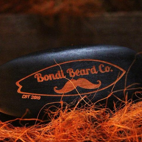 Image of Bondi Beard Co. Boar Bristle Brush positioned on copper hued fibres
