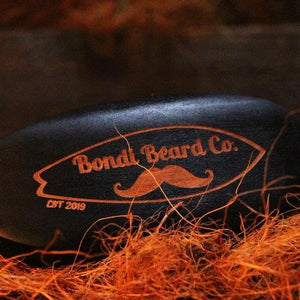 Image of Bondi Beard Co. Boar Bristle Brush positioned on copper hued fibres