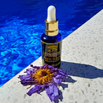 Load image into Gallery viewer, Image of Bondi Beard Co. Osiris Ancient Oil blend on ground next to vibrant blue swimming pool and dried blue lotus petals
