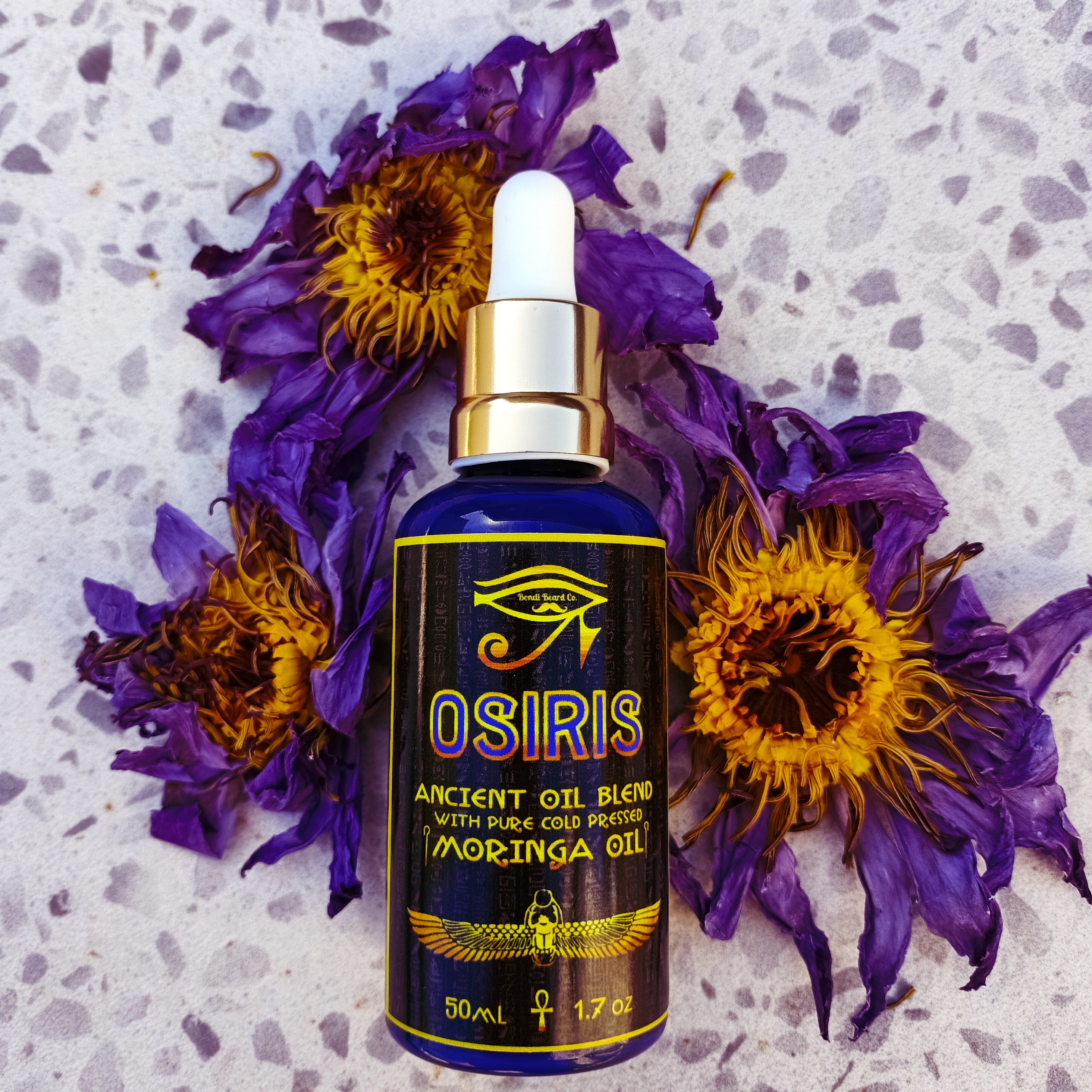 Image of Bondi Beard Co. Osiris Ancient Oil blend on ground with dried blue lotus petals