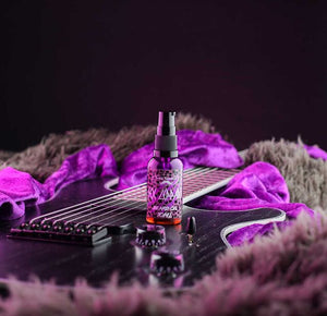 Image of Bondi Beard Co. Sex Leppard beard oil with bright purple leopard print label, spray bottle is placed on a black electric guitar and bright purple velvet and faux fur fabrics in background. 